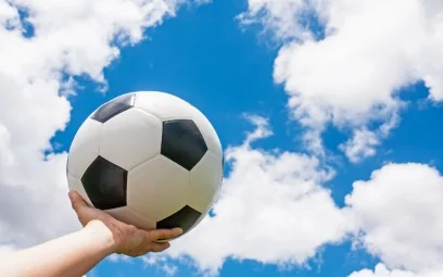 Holding football in a hand towards blue sky