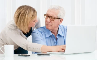 female helping mature male to use a computer