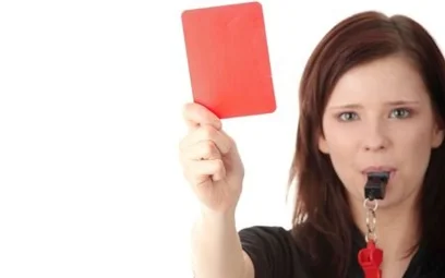 Female referrer blowing whistle holding red card
