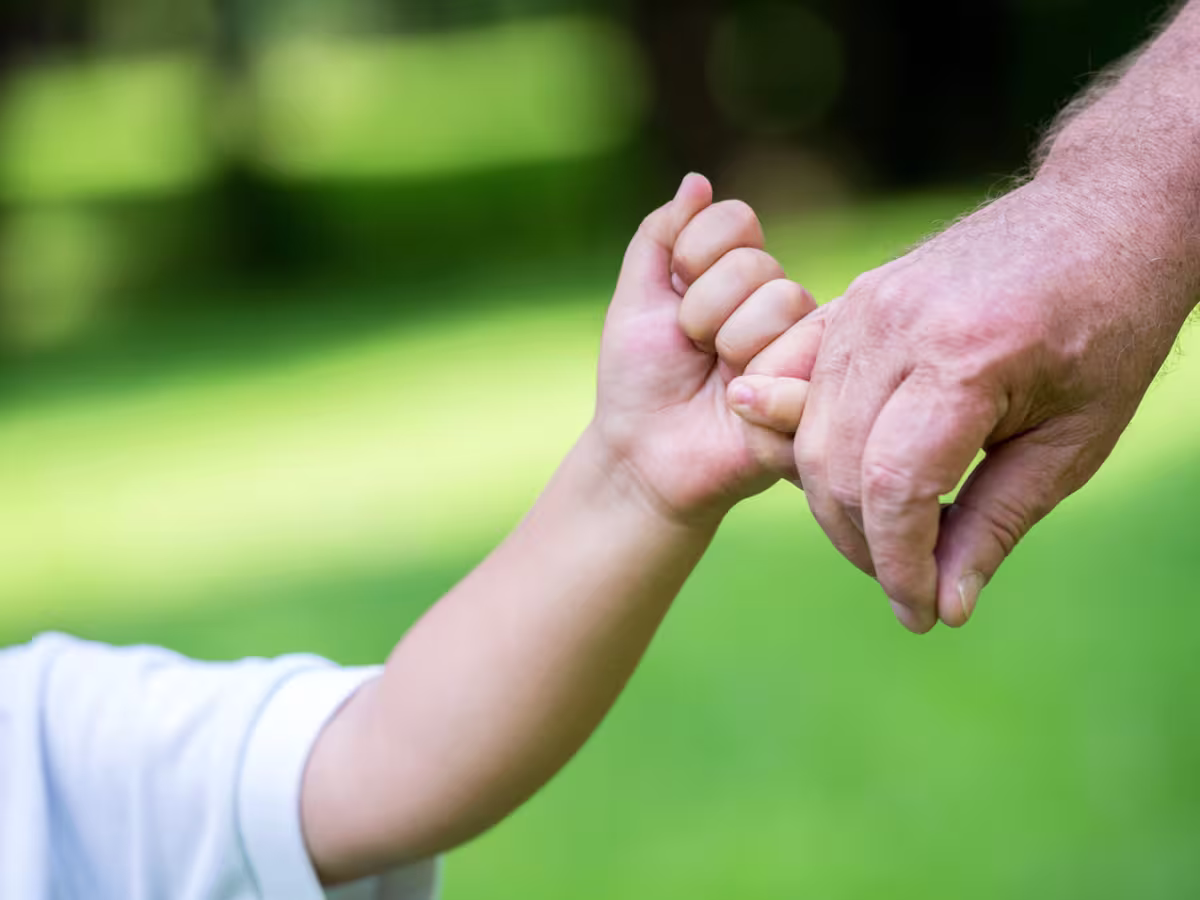 Child and grandfather holding hands - symbolising passing on wealth to the next generation