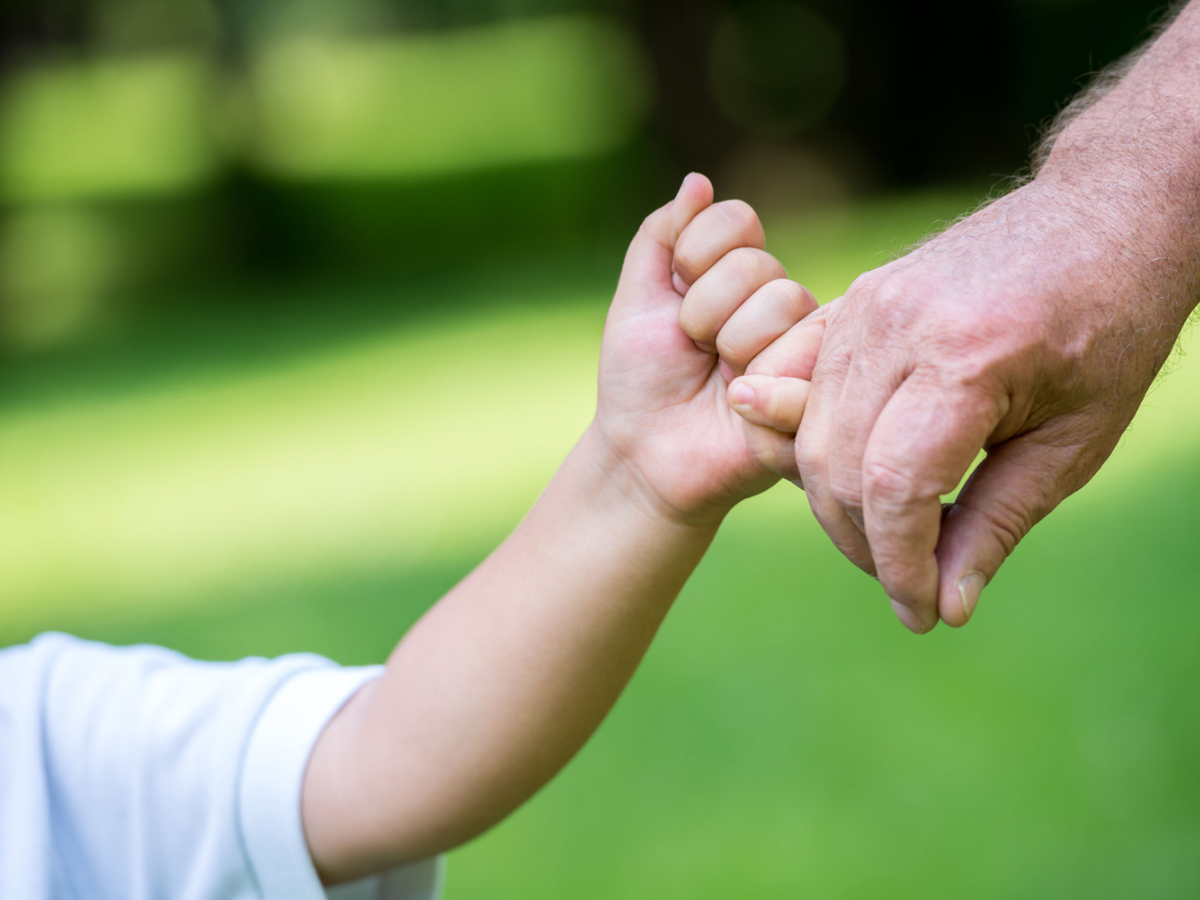 Child and grandfather holding hands - symbolising passing on wealth to the next generation