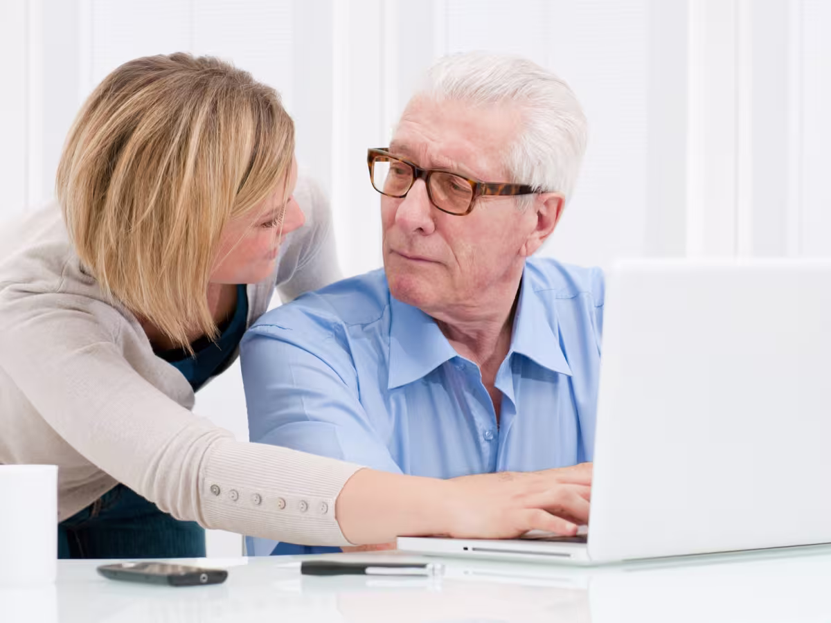 female helping mature male to use a computer