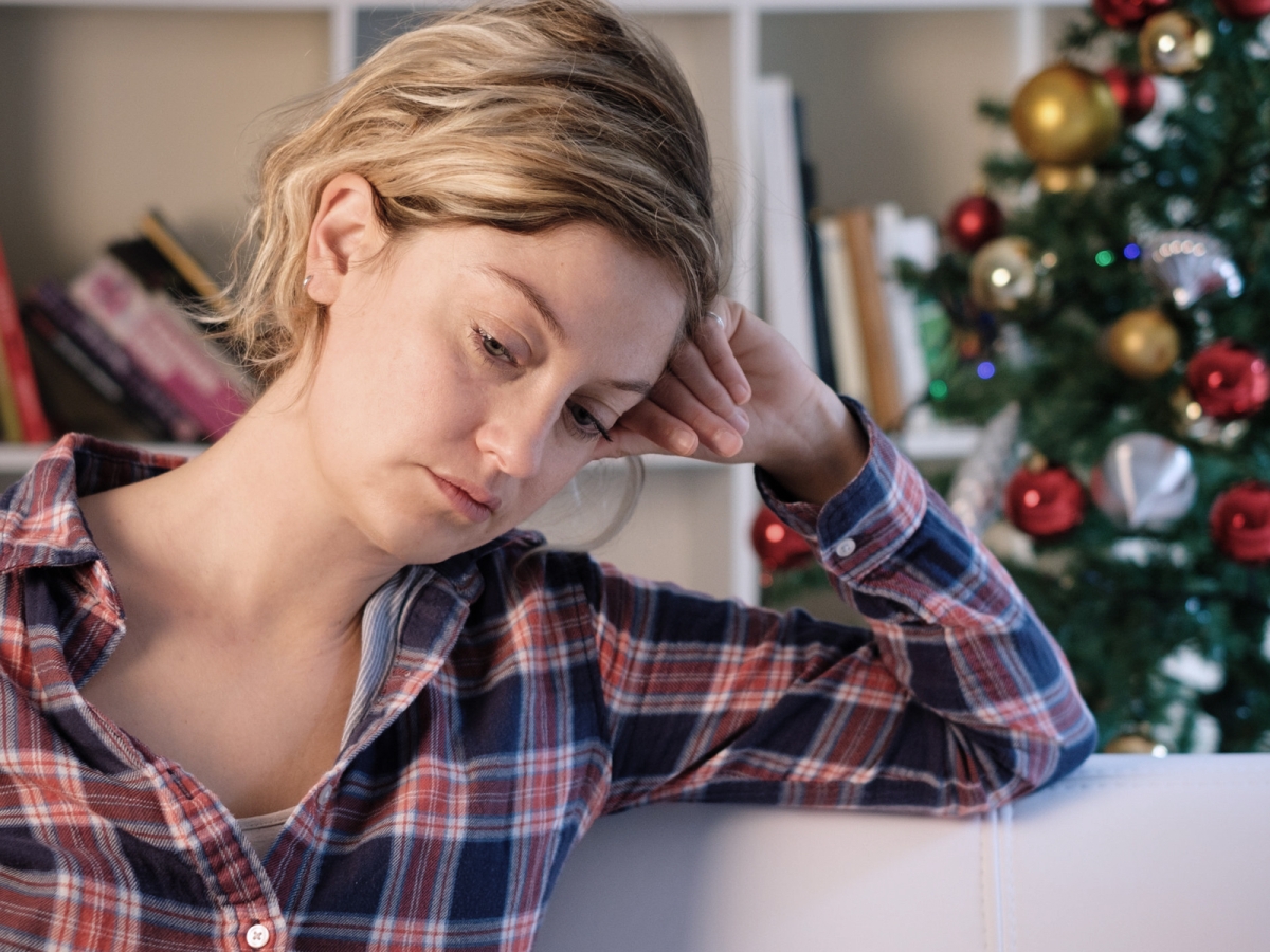 Christmas can be a difficult time for people suffering from abuse sad woman with a christmas tree in the background