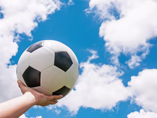 Holding football in a hand towards blue sky