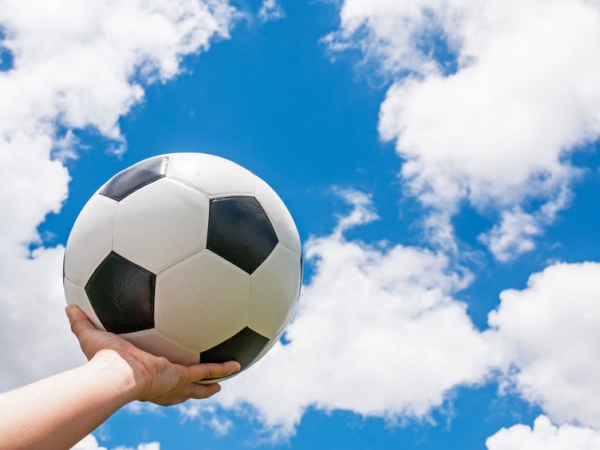 Holding football in a hand towards blue sky