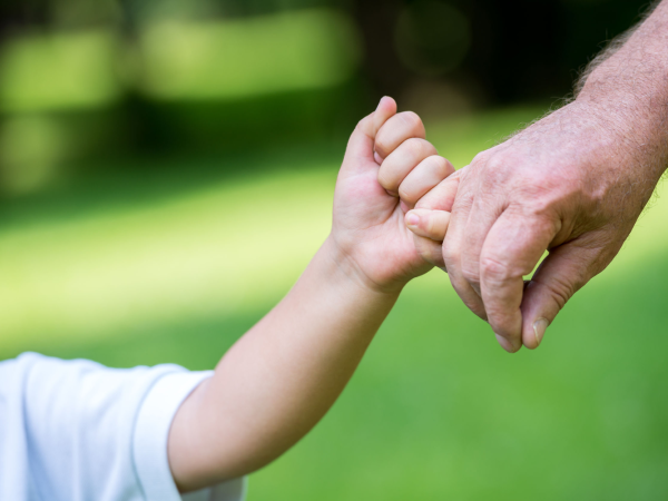 Child and grandfather holding hands - symbolising passing on wealth to the next generation