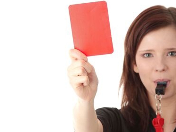 Female referrer blowing whistle holding red card