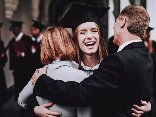 female student hugging parents at graduation