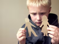 upset boy with paper people cut outs