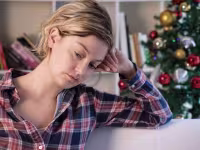 sad woman with a christmas tree in the background